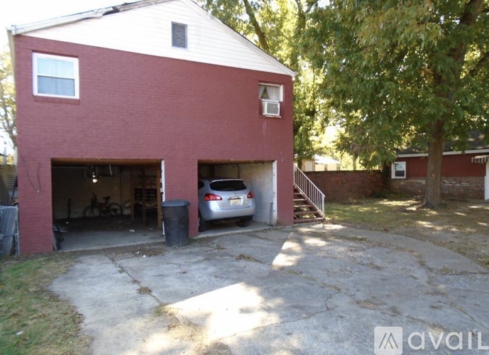A red brick house with a car in the garage.