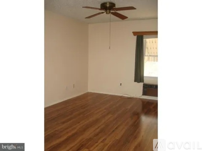A room with a ceiling fan and wooden flooring.