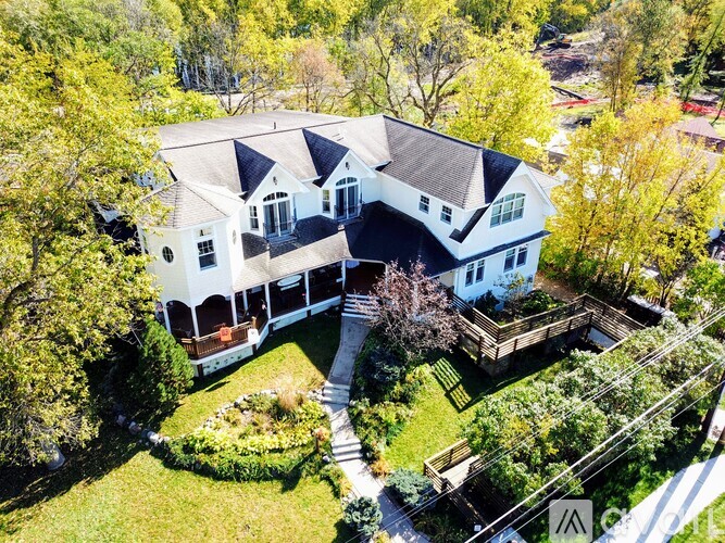 A large white house with a black roof and a large lawn.