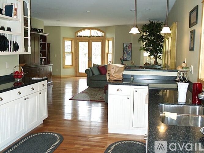 A kitchen with white cabinets and a wooden floor.