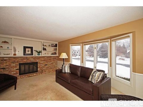 A living room with a brown couch and a fireplace.