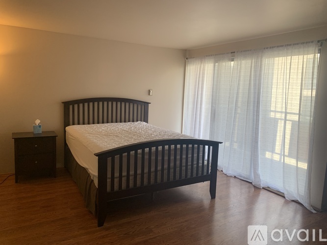 A bedroom with a large bed and a nightstand with a lamp on it.