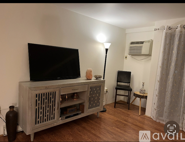 A room with a television, chair, and a lamp.