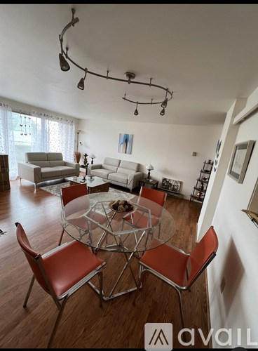 A modern living room with a glass table and red chairs.