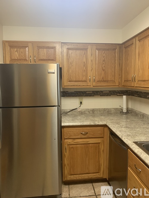 A kitchen with a stainless steel refrigerator and wooden cabinets.
