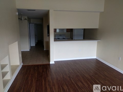 A room with wooden floors and a white wall with a shelf on it.