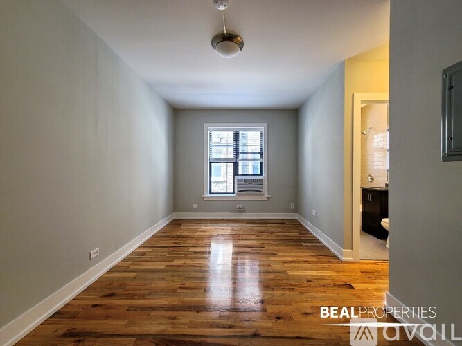 A spacious room with wooden flooring and a window.