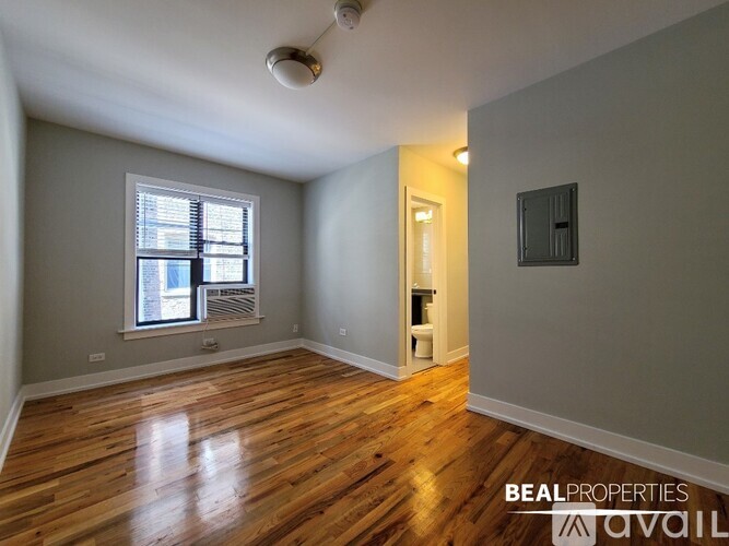 A room with wooden floors and a window with blinds.