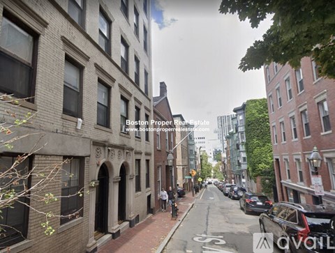 A street view of a residential area with parked cars and buildings on either side.
