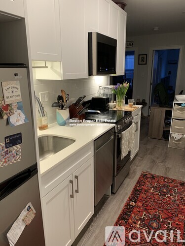 A kitchen with a refrigerator, sink, and stove.