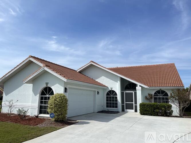 A white house with a red roof and a garage door.