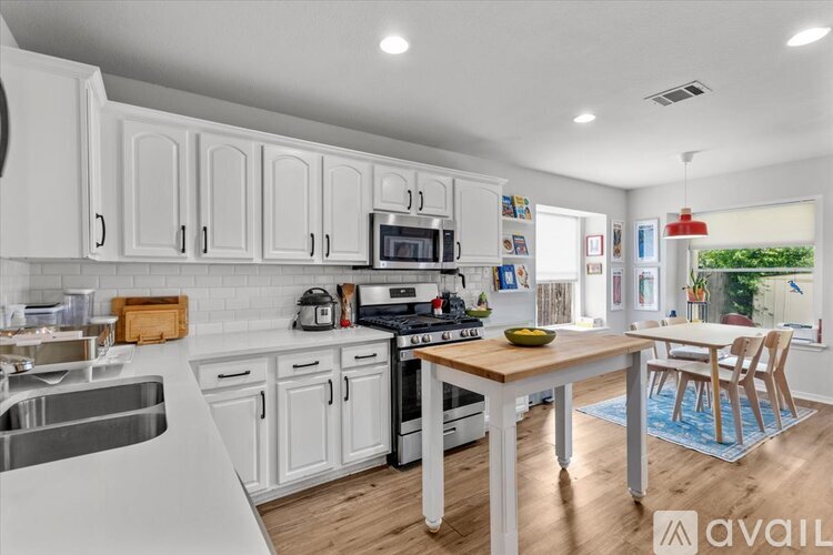 A kitchen with white cabinets and a wooden table.