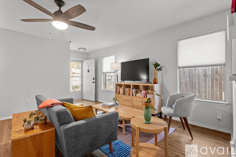 A living room with a grey couch, a wooden coffee table, and a ceiling fan.