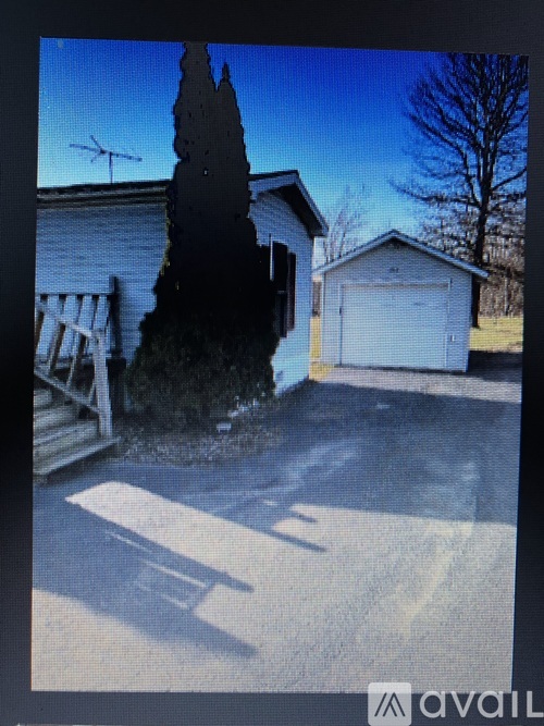 A house with a garage and a tree in front.