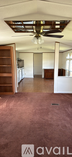 A room with a ceiling fan and a bed with a burgundy cover.