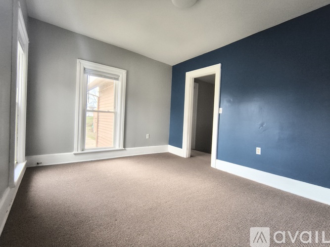 A room with a carpeted floor, a window, and a door.