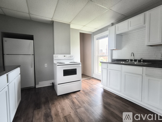 A kitchen with white cabinets and a black countertop.