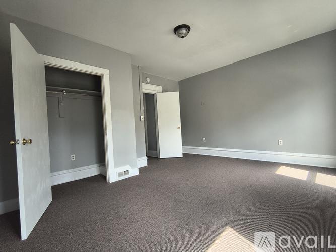 A spacious room with grey carpeting and white walls.