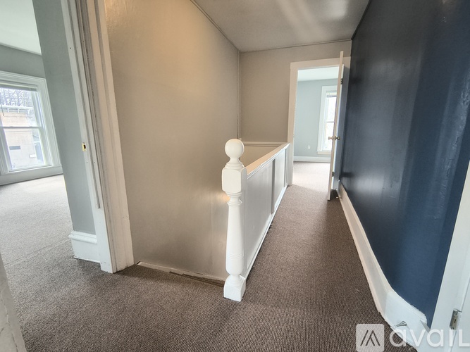 A hallway with a carpeted floor and white walls.