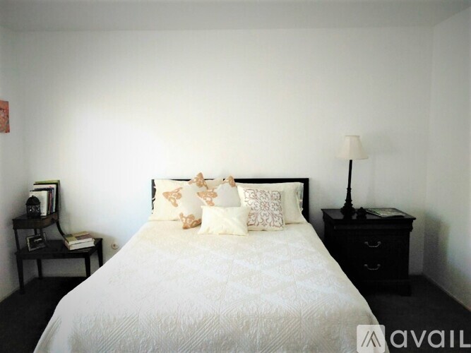 A bedroom with a white bed and a black nightstand.