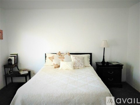 A bedroom with a white bed and a black nightstand.
