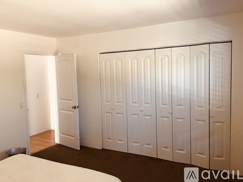 A room with a bed and a row of white doors.
