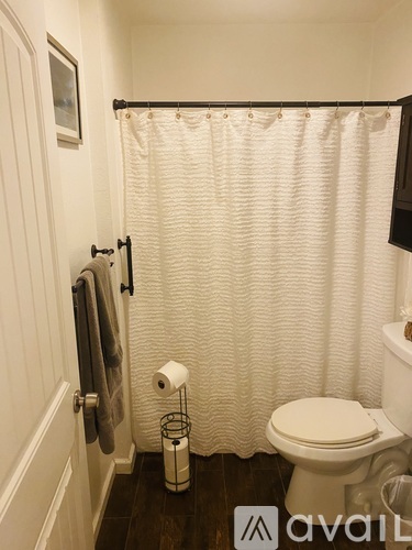 A white toilet sits under a shower curtain in a bathroom.