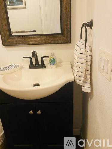 A white sink with a black faucet and a white towel hanging on a hook.