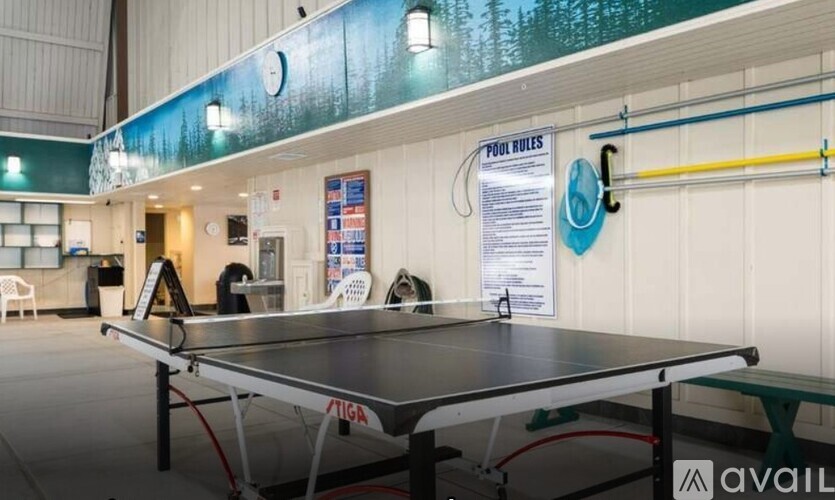 A ping pong table is in the middle of a room with pool rules on the wall.