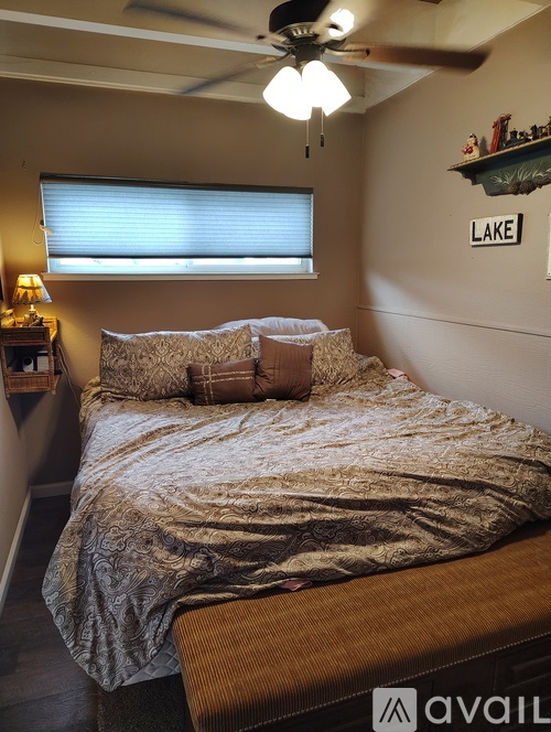 A bedroom with a bed, a ceiling fan, and a shelf with a sign that says "LAKE".