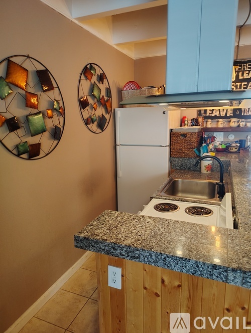 A kitchen with a granite counter top and a white fridge.