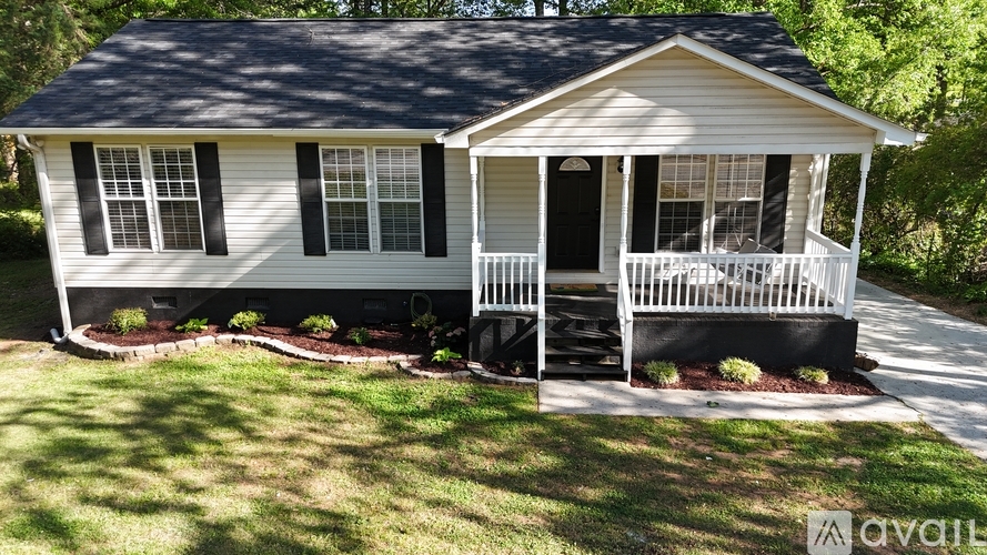 A two-story house with a porch and a white picket fence.