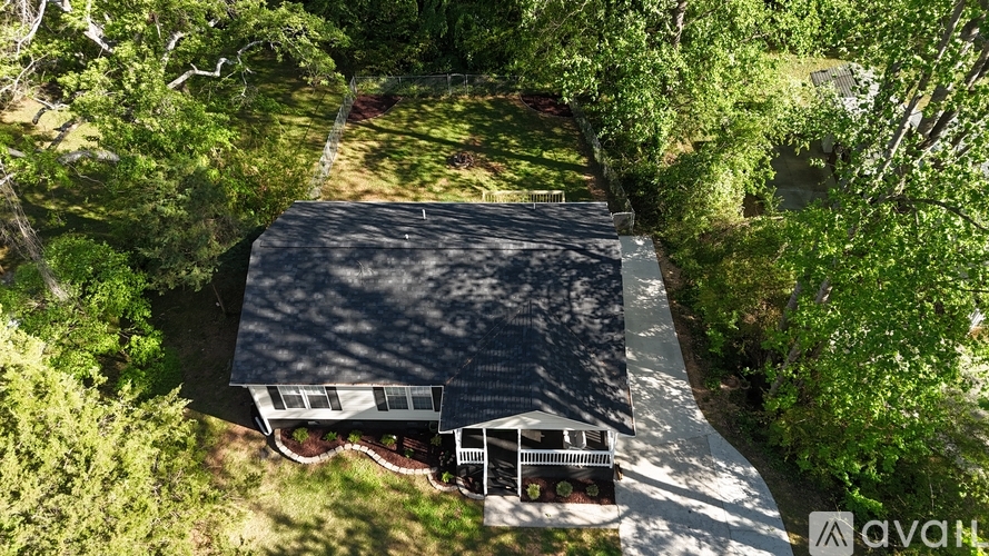 A house with a black roof is surrounded by trees.