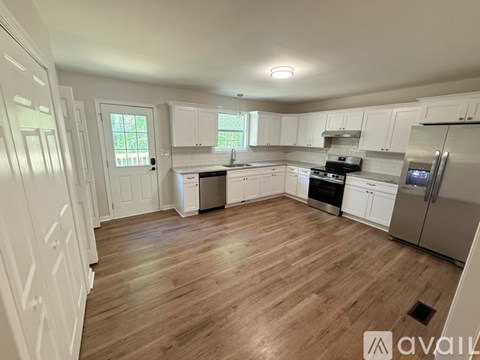 A kitchen with white cabinets and wooden flooring.