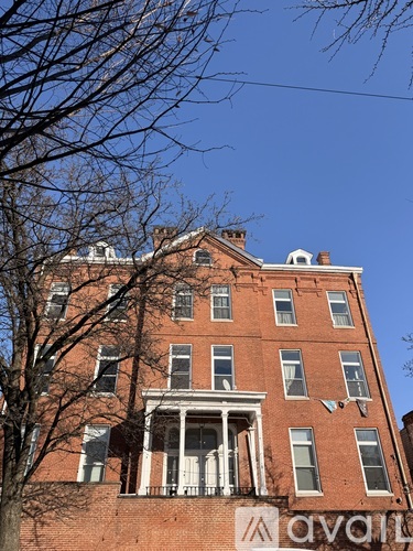 A tall red brick building with a balcony on the second floor.