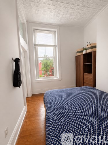 A bedroom with a bed, wooden cabinet, and a window.