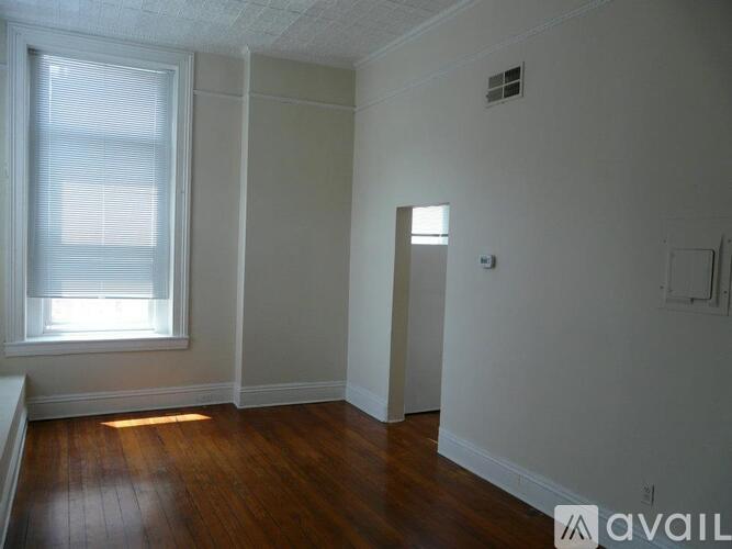 A room with a window and wooden floors is available for rent.