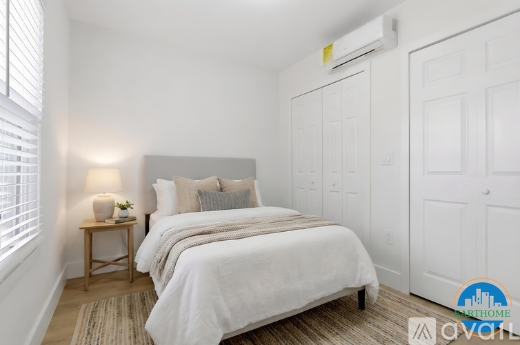 A bedroom with a bed, nightstand, and window with blinds.