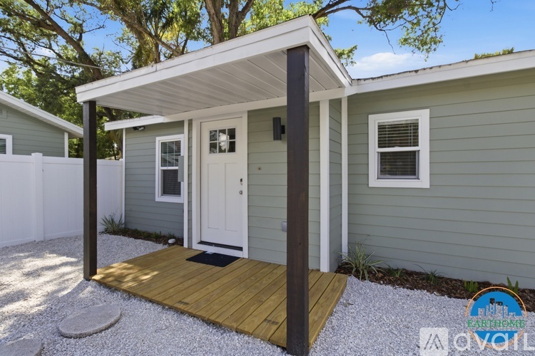 A small house with a white door and a wooden porch.