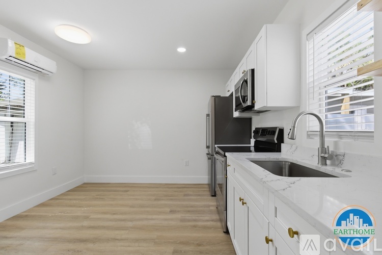 A kitchen with white cabinets and a black fridge.