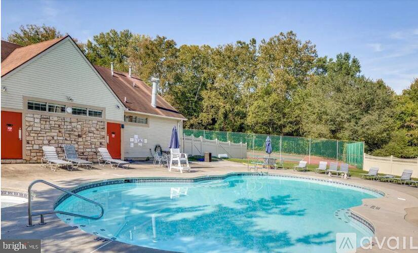 A pool with a house and trees in the background.