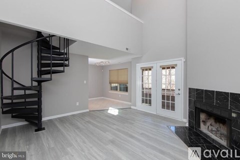 A living room with a fireplace and a spiral staircase.