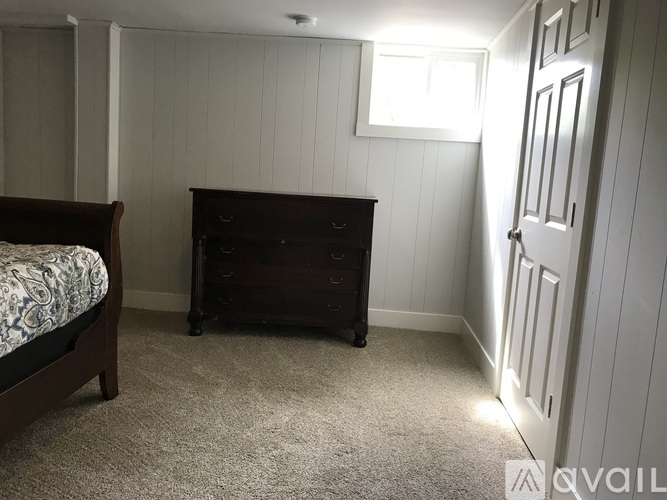 A bedroom with a bed, dresser, and window.