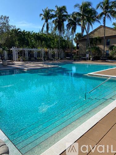 A large swimming pool surrounded by palm trees and a white pergola.