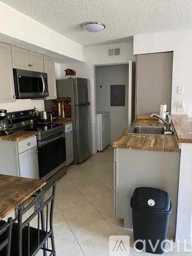 A kitchen with a stove top oven, microwave, refrigerator, and a sink.