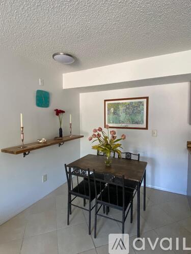 A dining room with a table set for two and a painting on the wall.