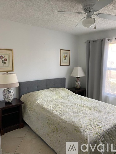 A bedroom with a bed, nightstands, and a ceiling fan.