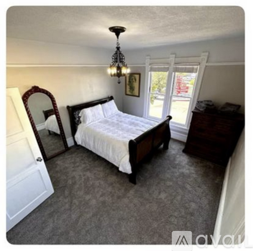 A bedroom with a bed, dresser, and mirror.
