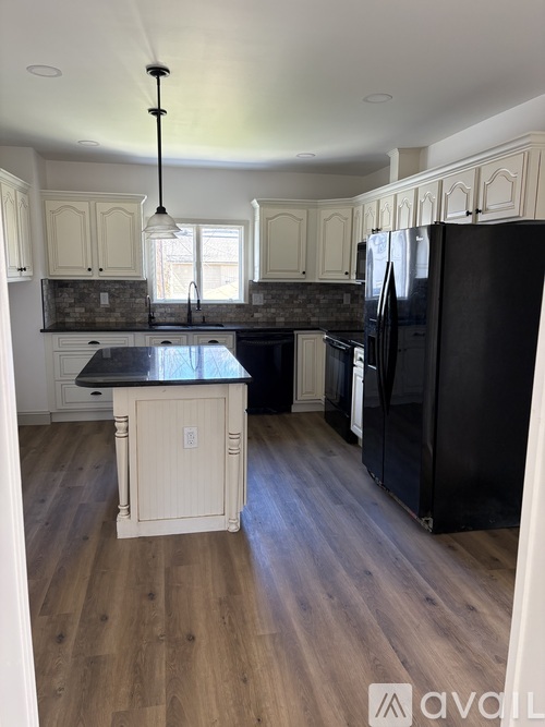 A kitchen with black appliances and wooden floors.