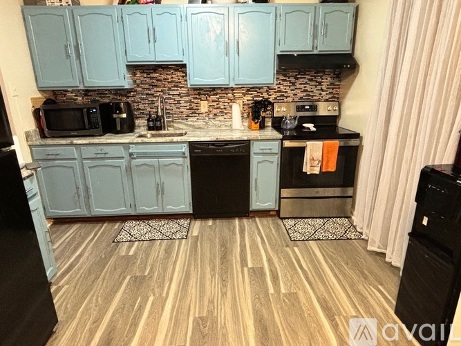 A kitchen with wooden floors and black appliances.